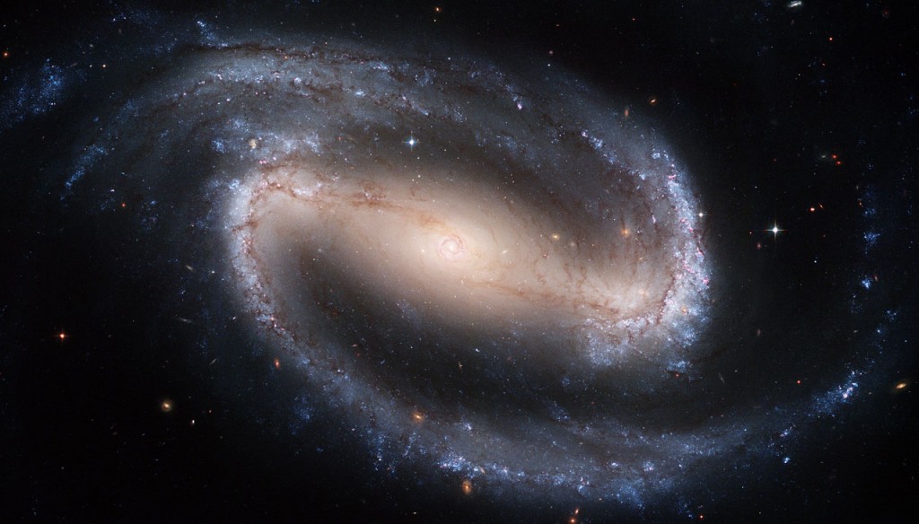 The Hubble telescope captured a display of starlight, glowing gas, and silhouetted dark clouds of interstellar dust in this 4-foot-by-8-foot image of the barred spiral galaxy NGC 1300. NGC 1300 is considered to be prototypical of barred spiral galaxies. Barred spirals differ from normal spiral galaxies in that the arms of the galaxy do not spiral all the way into the center, but are connected to the two ends of a straight bar of stars containing the nucleus at its center.